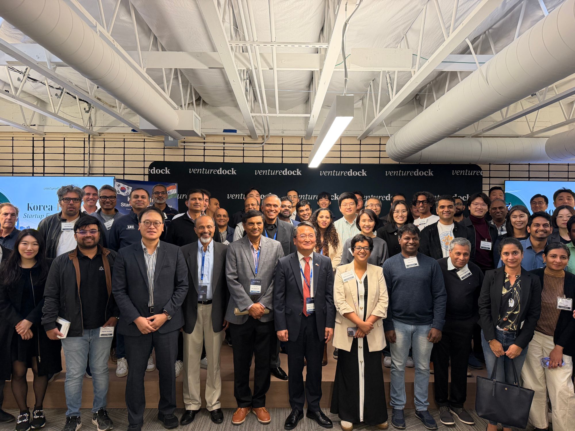 Speakers, organizers, and guests pose together in front of the Venture Dock backdrop
